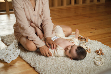 Mulher brincando com o seu filho em tapete no chão de madeira.