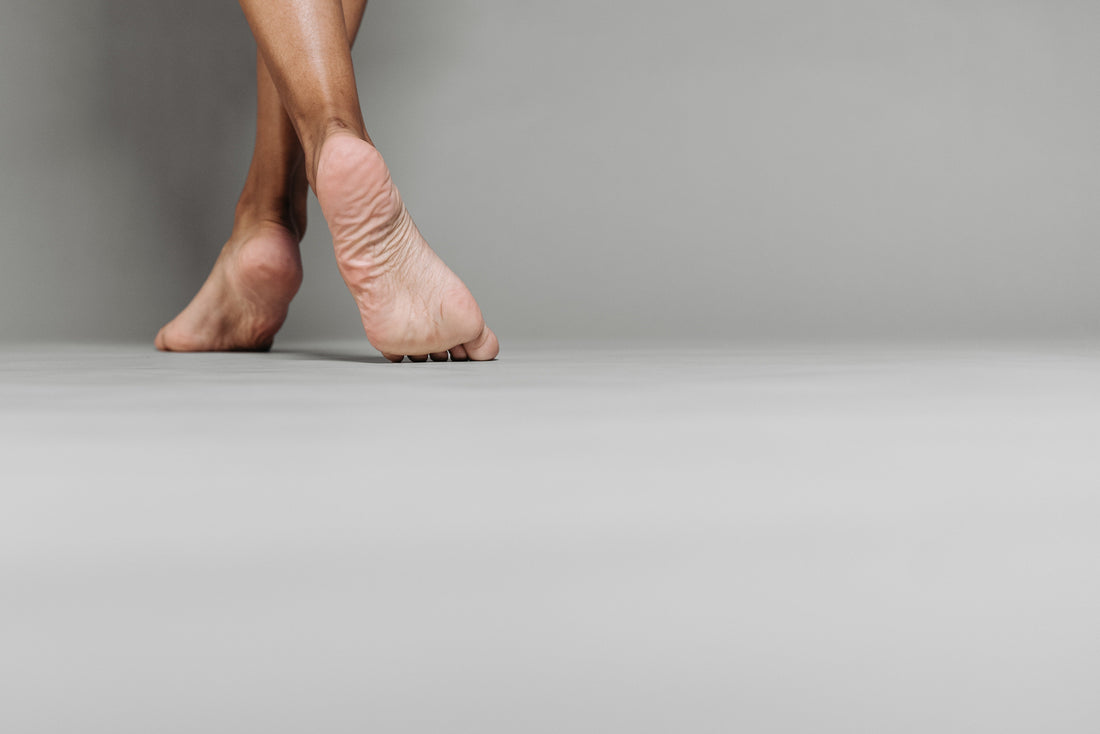 Pés descalços em movimento sobre superfície cinza, destacando conforto, naturalidade e conexão com o solo.