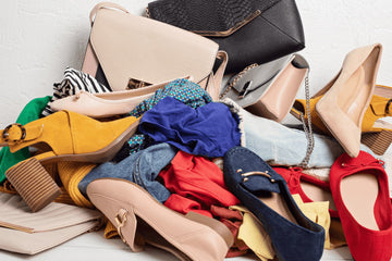 Pilha de sapatos, bolsas e roupas coloridas em desordem.