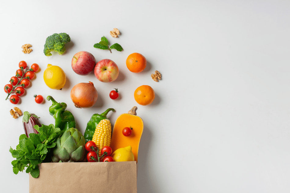 Sacola de papel com frutas e vegetais frescos, como tomates, maçãs, laranjas, milho e brócolis, sobre fundo branco.