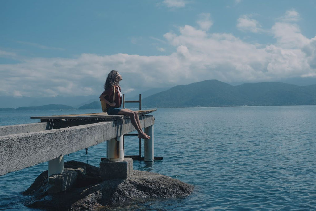 mulher sentada em uma ponte no mar