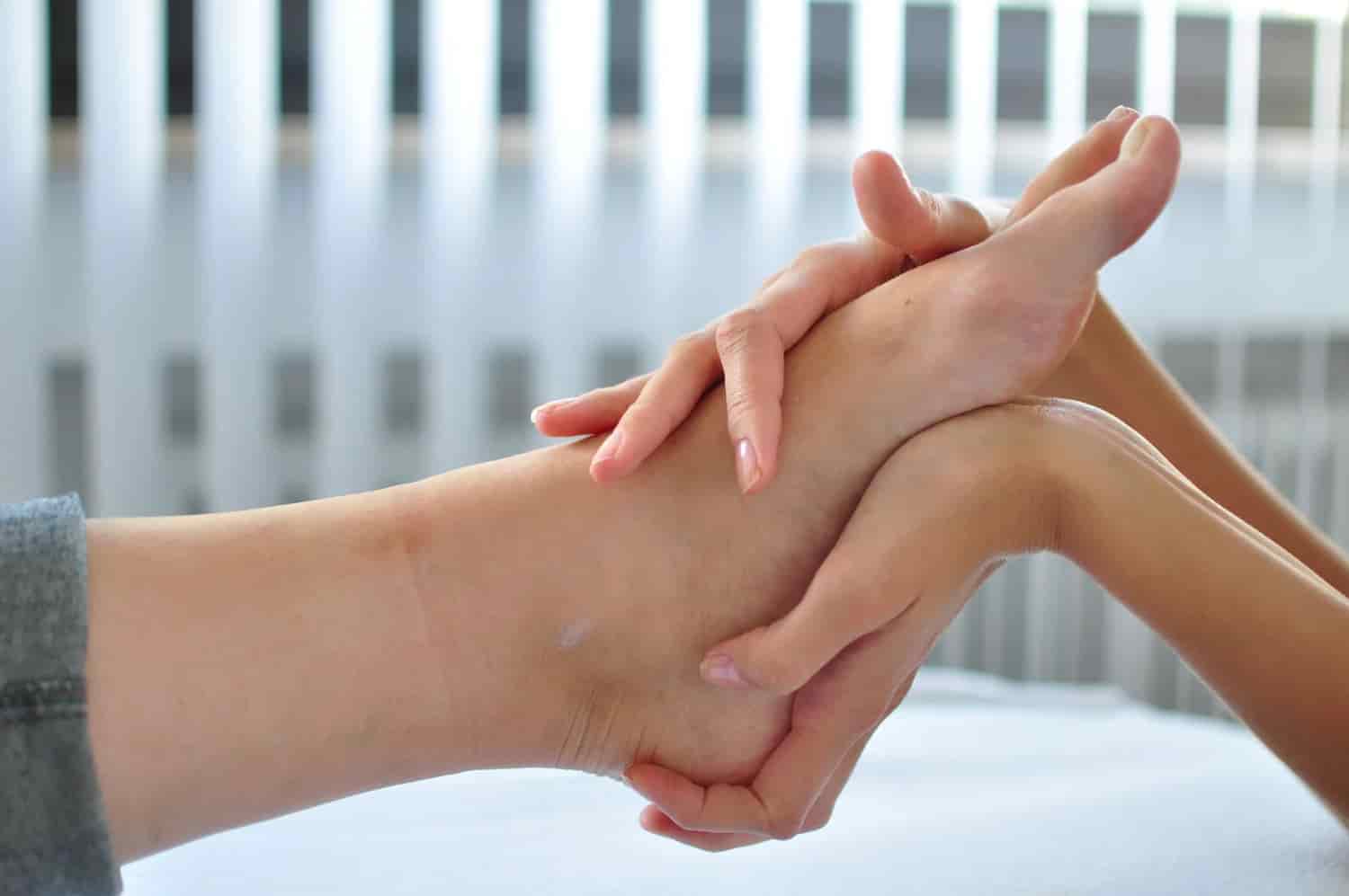 pé sendo massageados por uma mão 