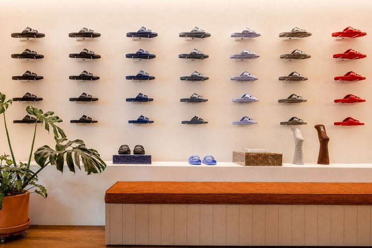 Sandálias Linus em diferentes cores expostas na parede da Casa Linus, uma das lojas físicas da marca para comprar os pares e acessórios pessoalmente