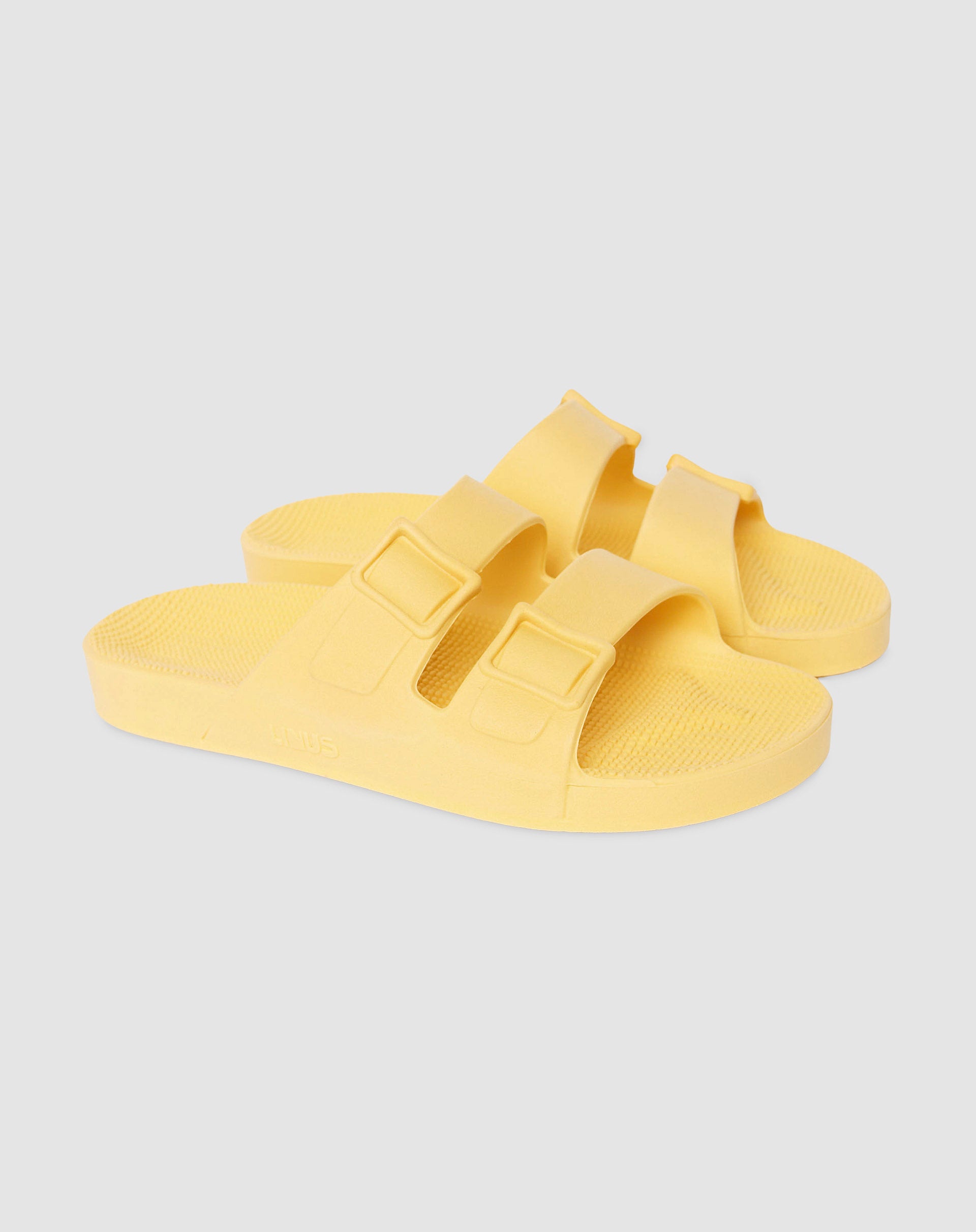 Par de sandália vegana na cor amarelo sol em fundo branco.