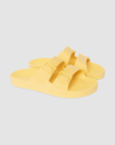 Par de sandália vegana na cor amarelo sol em fundo branco.