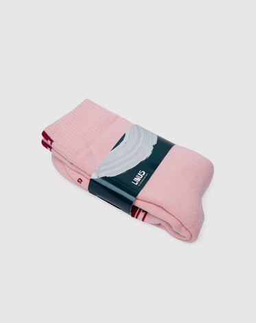 Meia de algodão da marca Linus na cor rosa dobrada e com a embalagem da marca em volta.