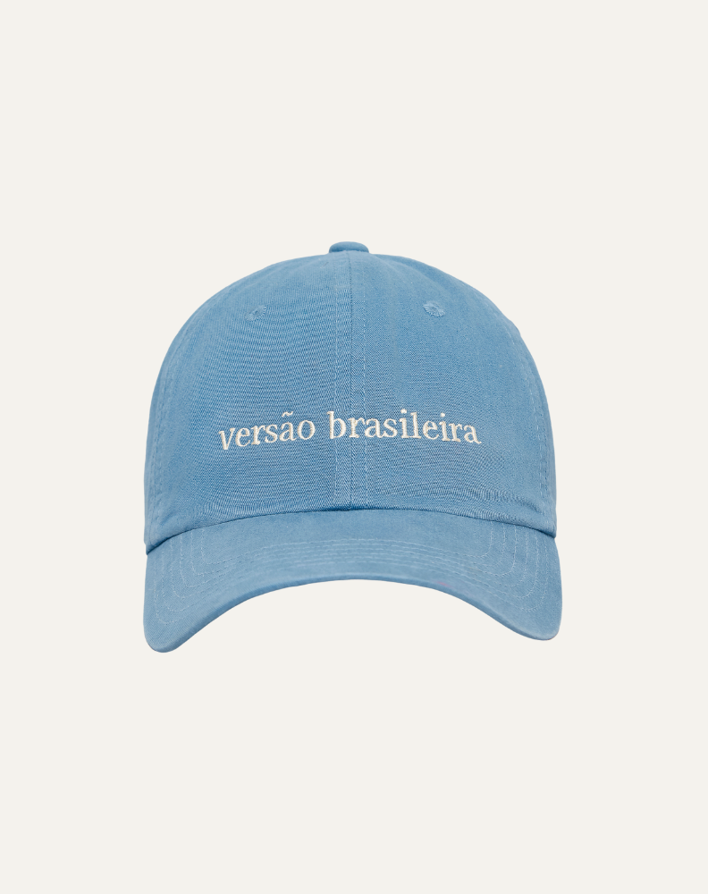 Boné em algodão na cor azul claro com bordado escrito versão brasileira em off white, vista frontal no fundo cinza claro.