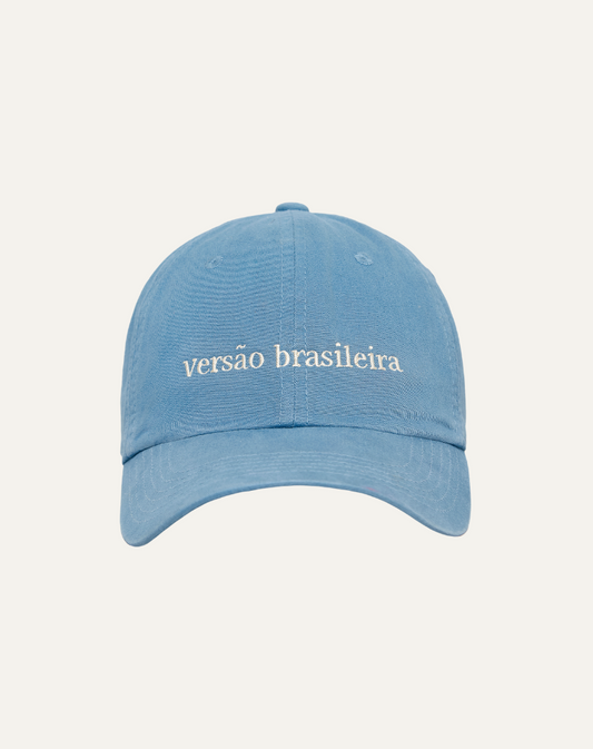 Boné em algodão na cor azul claro com bordado escrito versão brasileira em off white, vista frontal no fundo cinza claro.