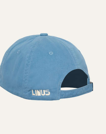 Boné em algodão na cor azul claro, vista lateral com detalhe de bordado em off white. Fundo da imagem em cinza claro.