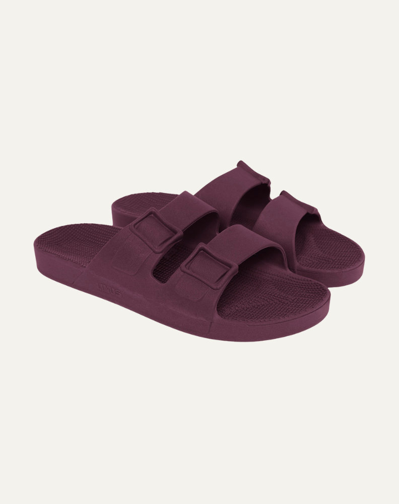 Par de sandália vegana na cor roxo açaí em fundo cinza claro.