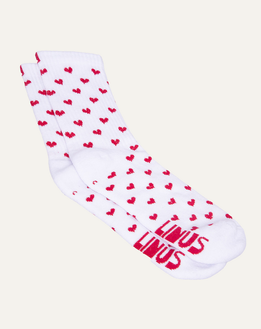 Par de meias de algodão com estampa de corações branca e vermelha em fundo cinza claro.